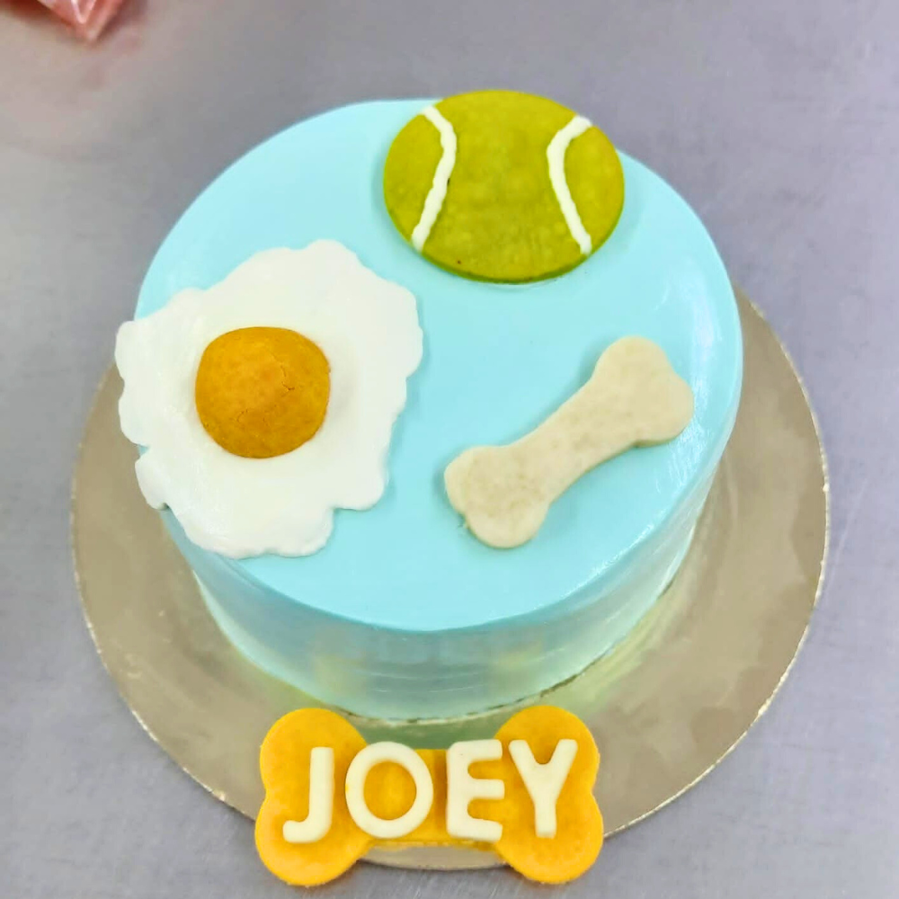 Cake for dog with tennis ball, egg and bone cookie toppers by Barker's Dozen Pet Bakery